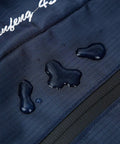 Close-up of water droplets on navy 50L Hiking Backpack For Men With Rain Cover Expandable 45L Plus 5L, showing waterproof material.