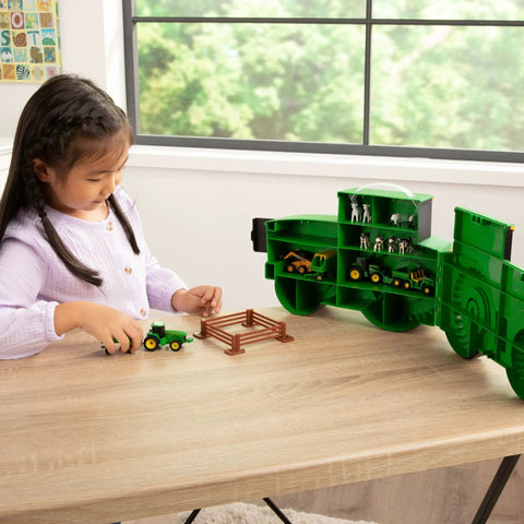 Child playing with John Deere Tractor Toys Value Set With Portable Carrying Case on a table, displaying die-cast vehicles and compartments.