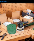 50 pc 5-inch sanding discs with 8 holes and random orbital sander on workbench showcasing durable zirconia abrasive.