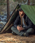 Man under Tough As Nails Heavy Duty Survival Blanket With Reflective Thermal Layer For Camping And Outdoor Gear Waterproof Tarp Or Shelter 8.5 Ft By 12 Ft Olive Green All Weather Ready