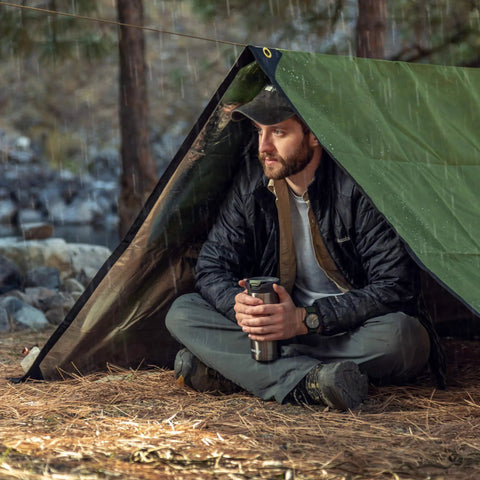 Man under Tough As Nails Heavy Duty Survival Blanket With Reflective Thermal Layer For Camping And Outdoor Gear Waterproof Tarp Or Shelter 8.5 Ft By 12 Ft Olive Green All Weather Ready