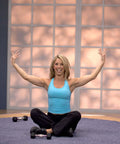 Woman exercising in front of large window, demonstrating a routine from Single DVD Get Fit Daily Dozen - 5 x 12-Minute Home Routines.