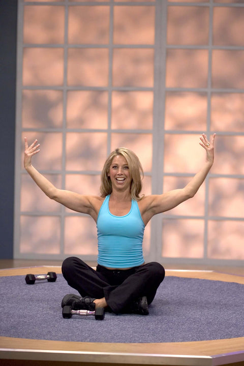Woman exercising in front of large window, demonstrating a routine from Single DVD Get Fit Daily Dozen - 5 x 12-Minute Home Routines.