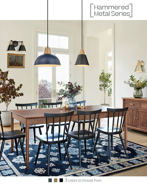 Dining room with two hanging lights from Hammered Metal Series above wooden table, with chairs and decorative plants in background.