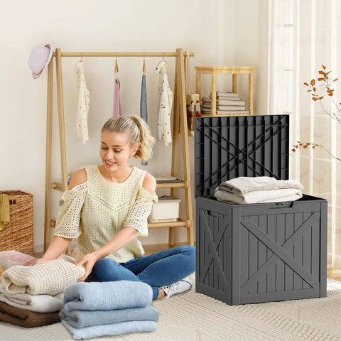 36 Gallon Outdoor Deck Box Waterproof Lockable Resin Storage Chest in use, with towels in a home setting beside a woman folding clothes.