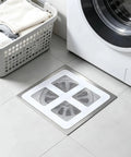Hair Drain Stickers 100 Pcs Disposable Peel Stick applied on floor near washing machine and laundry basket.
