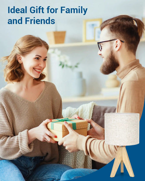 Couple exchanging gifts with a Boho Wood Tripod Table Lamp With Linen Fabric Shade for cozy living room ambiance.