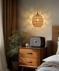 Homebody Essential Plug In Pendant Light Featuring Hand Woven Rattan And Wicker Egg Shade With 15 Ft Cord above a nightstand.