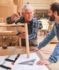 Two carpenters discussing woodworking project using F Style Bar Clamp 7 Inch By 16 Inch With 1320 Pound Clamping Force in workshop.
