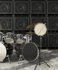 Foldable Silent Snare Drum Stand Eco Friendly Practice Rack beside a black drum set and speaker wall setup.