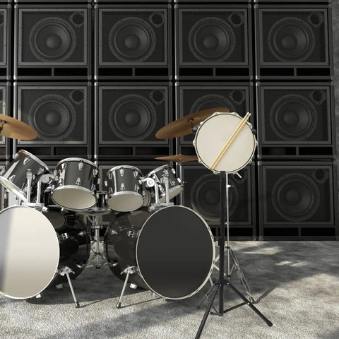 Foldable Silent Snare Drum Stand Eco Friendly Practice Rack beside a black drum set and speaker wall setup.