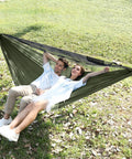 Couple relaxing in Camping Hammock With Mosquito Net And Ridge Rope For Two, Extra Large 114x55 Inch at outdoor park.