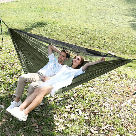 Couple relaxing in Camping Hammock With Mosquito Net And Ridge Rope For Two, Extra Large 114x55 Inch at outdoor park.