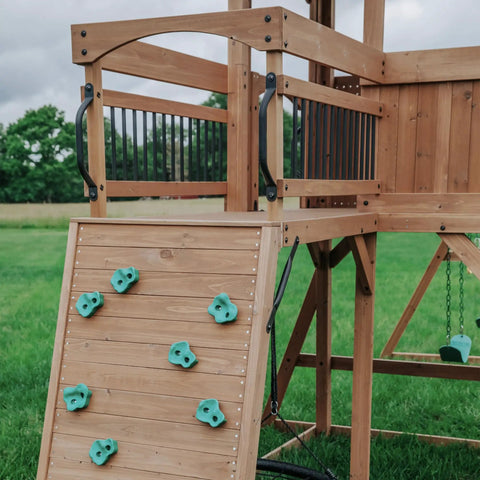 Cedar Wood Swing Set With Wave Slide And Raised Clubhouse Plus Balcony, featuring wooden climbing wall and balcony.