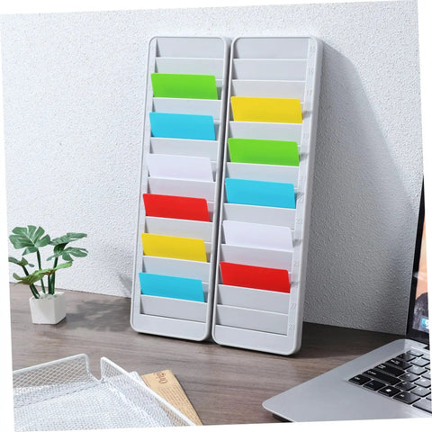 Solid As A Rock Wall Mount Id Card Holder Rack Featuring 28 Spacious Openings Crafted From Bump Resistant Polymer Plastic For Tight Cluttered Offices Warehouses And Clock In Areas on a desk with colorful ID slots.