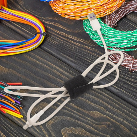 Reusable Black Polyester Cable Ties For Desk Wire Management Heavy Duty Cord Straps For Computer Setup Electronic Organizer securing loose USB cable on wooden surface.
