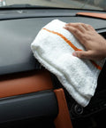 60 Pack 16 By 19 Inch Terry Bar Mop Rags For Cleaning Absorbent And Durable Cotton Cloths Multipurpose Shop Towels Reusable Rags For Home Office Garage Kitchen And More. White cotton rag with an orange stripe wiping a car dashboard.
