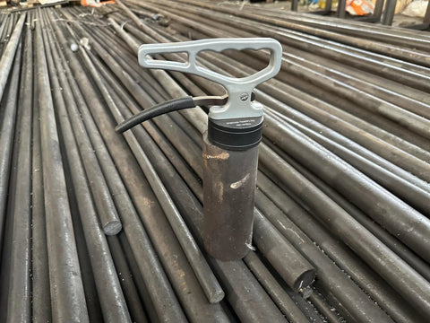 MUTUACTOR magnetic pickup tool with release handle; grey handle, black magnet housing, resting on steel rods.