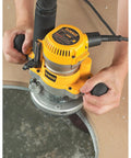 User operating Adjustable Plunge Router Base For DW616 And DW618 Routers with tool-free steel cam lock on round wood surface.