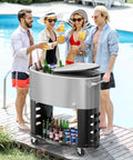 70 Qt Rolling Patio Cooler on Wheels with Bottle Opener and Ice Scoop, portable ice chest for backyard parties by poolside, holds 87 cans or 48 bottles, shown with drinks on bottom shelf.