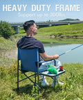 Man fishing seated on Directors Chair For Outdoors With Side Table Foldable Camping Chair For Adults, blue grey, by a lake.
