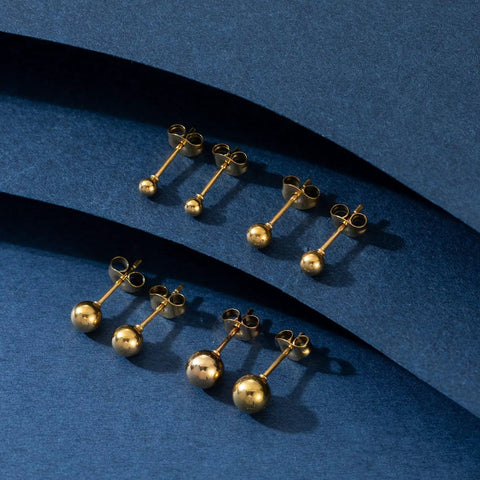 Four Pairs Gold Stud Earrings For Women Set, 14K Gold Plated Ball Studs In Stainless Steel, Classic And Modern Styles, Hypoallergenic Everyday Bling Jewelry, Lightweight Shine For Any Outfit. Four gold ball stud pairs on blue background