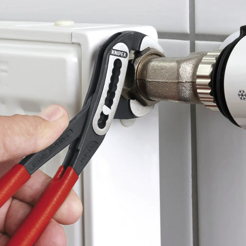 Close-up of Three Piece Water Pump Pliers Set 7 10 And 12 Inch With Heavy Duty Groove Pliers for pipes in use on a radiator valve.