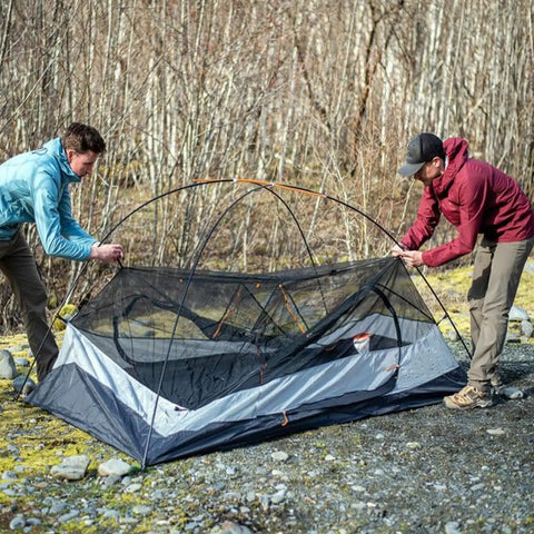Two campers setting up a tent using One Eighth Inch Sixty Feet Tent Pole Shock Cord Replacement Kit With Lead Wire, Washers And Clip.