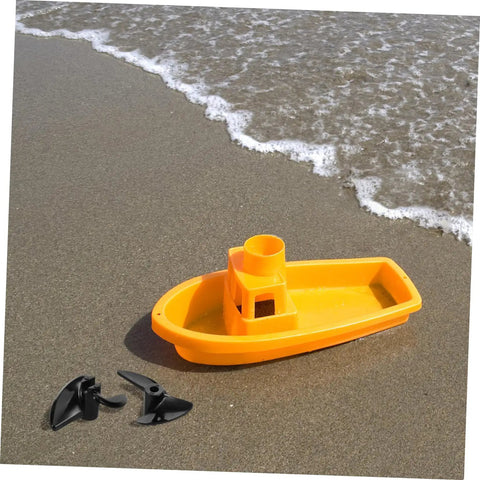 Two Pack CNC Model Ship Propellers For RC Boats next to yellow toy boat on sandy beach, showcasing precision balanced blades.