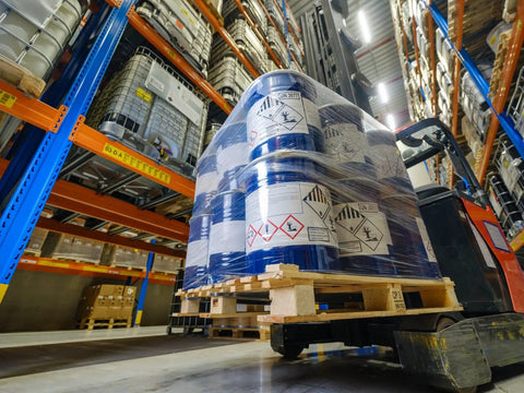 Forklift carrying wrapped barrels in warehouse, showcasing Red Up Arrow Shipping Labels Orientation Stickers, Heavy Duty 3 x 4.125 Inch.