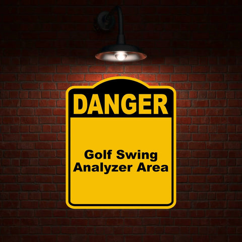 Golf Swing Danger Area Sign In Yellow And Black Aluminum Composite Construction Rust Resistant Weatherproof Pro Grade Warning Plate For Golf Practice Range against a brick wall.