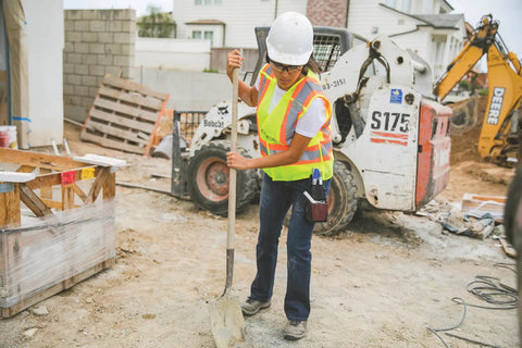 Men's High Vis Reflective Breakaway Safety Vest With Contrast Mesh And Quick Hook Closure Ansi Class Two Jobsite Ready Traffic Control Utility Gear Lime Orange Trim Real Big Size Built Tough worn by a worker shoveling on a construction site.