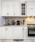 Brushed Brass And Brushed Nickel Cabinet Pulls 5 Inch Center To Center Curved Handles installed on white kitchen cupboards.