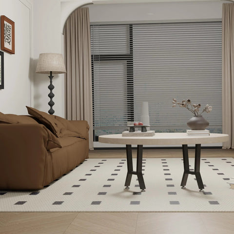 Pair of H-shaped black metal coffee table legs (15-inch) supporting a round beige tabletop in a living room.