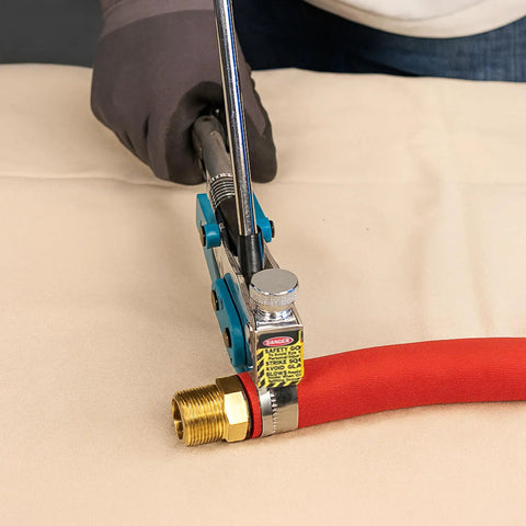 Top Shelf Center Punch Installer With Built In Cutter For 5/8 And 3/8 Inch Hose Clamps Knockout setup, tightening a red hose clamp on brass fitting.