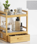 Two Tier Bathroom Countertop Organizer With Hidden Drawer Bamboo Vanity Storage For Skincare And Makeup Open Shelves And Pull Out Drawer Perfect Space Saver For Everyday Essentials For Kitchen Coffee Bar Or Matcha Station With Stone Drying Mat in a bathroom setting