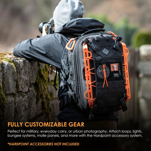 Photographer wearing Impact-Resistant Hardshell Camera And Drone Backpack With External Mounting System For Photographers, Content Creators And Drone Pilots, Rugged Water-Repellent Case, Multi-Compartment Organization, Go-To Grayman-Style Gear Carrier, showcasing customizable orange exterior.