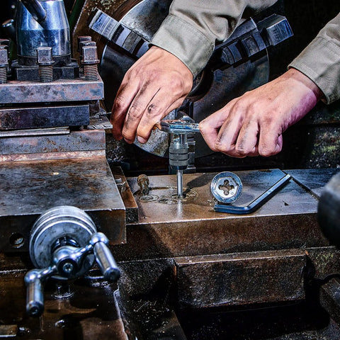 Hands using a Reversible Ratcheting T Handle Tap Wrench for precise automotive threading with a smooth reverse action.