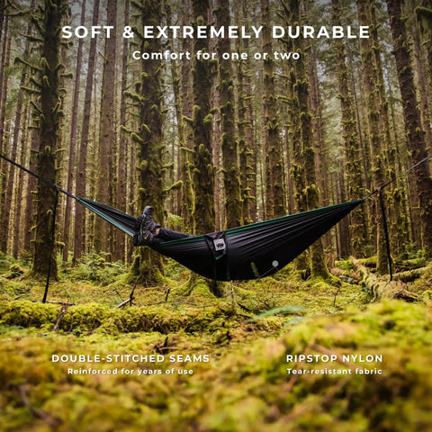 All In One Camping Hammock Kit With Bug Net And Rain Fly for Easy Setup in mossy forest, featuring ripstop nylon hammocked person.