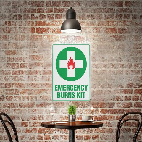 Emergency Burn Care Sign 8x12 Inches Aluminum Warning Plate for indoor use displayed on brick wall in cafe setting.