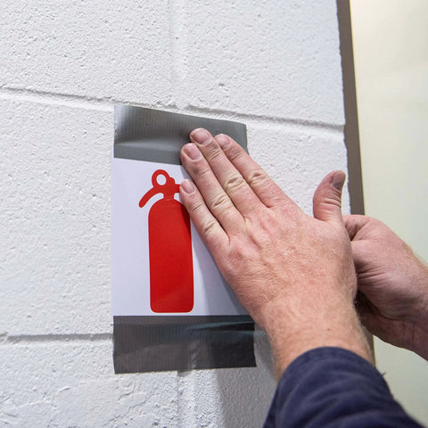 Hands applying Value Duct Tape 1900 Single Roll, Silver Thin Cloth-Backed Film with High-Tack Synthetic Rubber Adhesive on sign