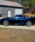 Top Shelf Tinted Blue Paint Basecoat Gallon Ready To Spray With Slow Reducer Blend For Ultra Smooth Automotive Finish That Hits Perfect And Looks Totally Fresh On Any Ride on a sleek black convertible car in a garage.