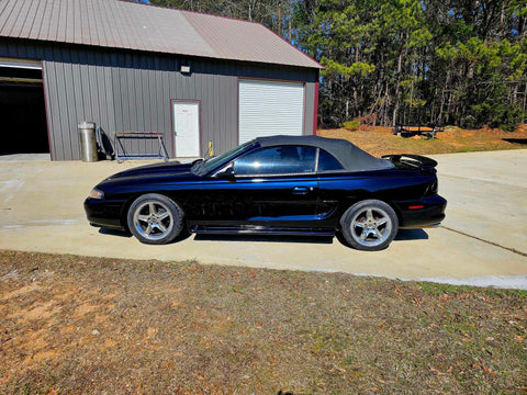 Top Shelf Tinted Blue Paint Basecoat Gallon Ready To Spray With Slow Reducer Blend For Ultra Smooth Automotive Finish That Hits Perfect And Looks Totally Fresh On Any Ride on a sleek black convertible car in a garage.