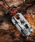 Close-up of Viking Spark Whetstone Sharpener And Fire Starter Necklace on wooden surface displaying ferrocerium rod and pendant.