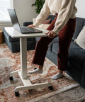 Person using Adjustable Rolling Laptop Desk With Wheels For Home Office Or Classroom Sit Stand Cart On The Go Mobility 23.6 By 20.5 Inch Desktop White Height 29.6 To 44.2 Inches in living room