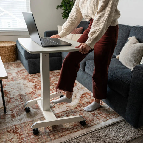 Person using Adjustable Rolling Laptop Desk With Wheels For Home Office Or Classroom Sit Stand Cart On The Go Mobility 23.6 By 20.5 Inch Desktop White Height 29.6 To 44.2 Inches in living room