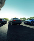 Rear view of three BMW sedans in a parking lot. Highlighting BMW Hubcap Replacement 36 13 6 783 536 Black Fits Most Original BMW Wheels.