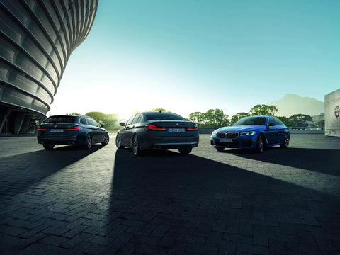 Rear view of three BMW sedans in a parking lot. Highlighting BMW Hubcap Replacement 36 13 6 783 536 Black Fits Most Original BMW Wheels.
