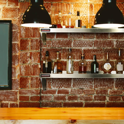 Stainless Steel Wall Shelf 24 Inch Wide by 12 Inch Deep, Heavy Duty Beefed Up Commercial Grade Storage in bar with liquor bottles.