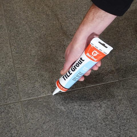 Hand applying Pre Mixed Tile Grout For Walls And Floors White 5.5 Oz Pro Quality With Excellent Adhesion Easy To Use And Water Clean Up Ideal For Ceramic And Mosaic Tiles Adheres To Tile Masonry Wood And Wallboard Made In USA to floor tiles